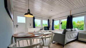 Ein modernes Wohnzimmer mit Essbereich, großen Fenstern und einer gemütlichen Sitzecke.