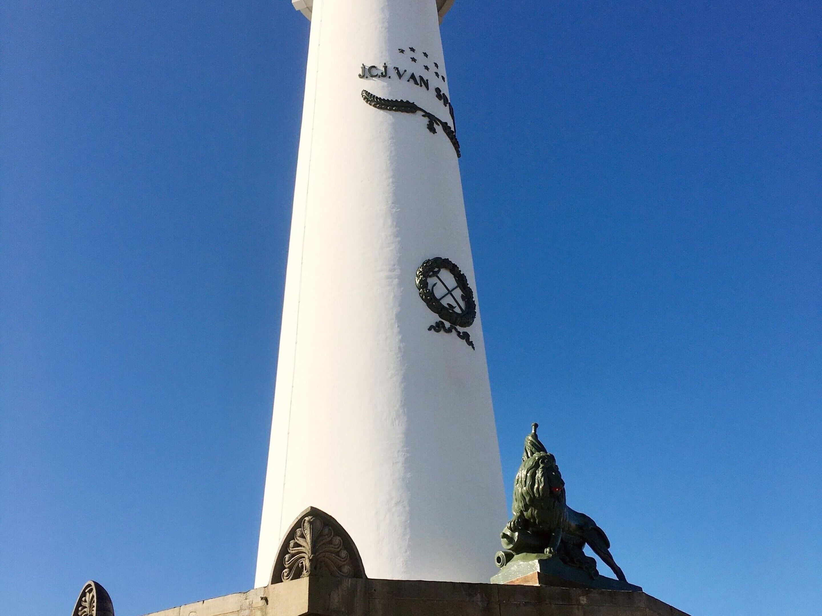 Uma torre branca e alta, com um relógio e uma estátua de leão na base.