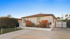A single-story house with a garage, a well-maintained lawn, and a gated driveway. - Boho Bungalow Studio Walk to Beach (San Diego)