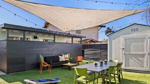 A backyard with a dining table, chairs, a sofa, and a small play area. - Boho Bungalow Studio Walk to Beach (San Diego)