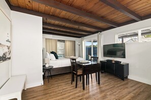 A modern room with a wooden ceiling, a bed with curtains, a dining table with chairs, a TV on the wall, and a window with blinds. - Pacific Beach Studio Short Walk to Ocean (San Diego)