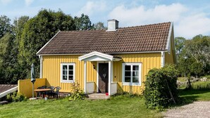 A yellow house with a brown roof, a front porch, and a small garden area. - 4 Person Holiday Home in Virserum (Virserum)