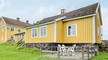 A yellow building with a balcony and outdoor seating.