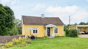 A yellow house with a brown roof, a front porch, and a small garden area. - 4 Person Holiday Home in Virserum (Virserum)