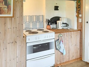 Una cocina con estufa, horno y cafetera.