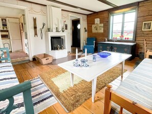 A cozy room with a fireplace, a dining table with blue and white plates, and a window with a view. - 4 Person Holiday Home in Virserum (Virserum)