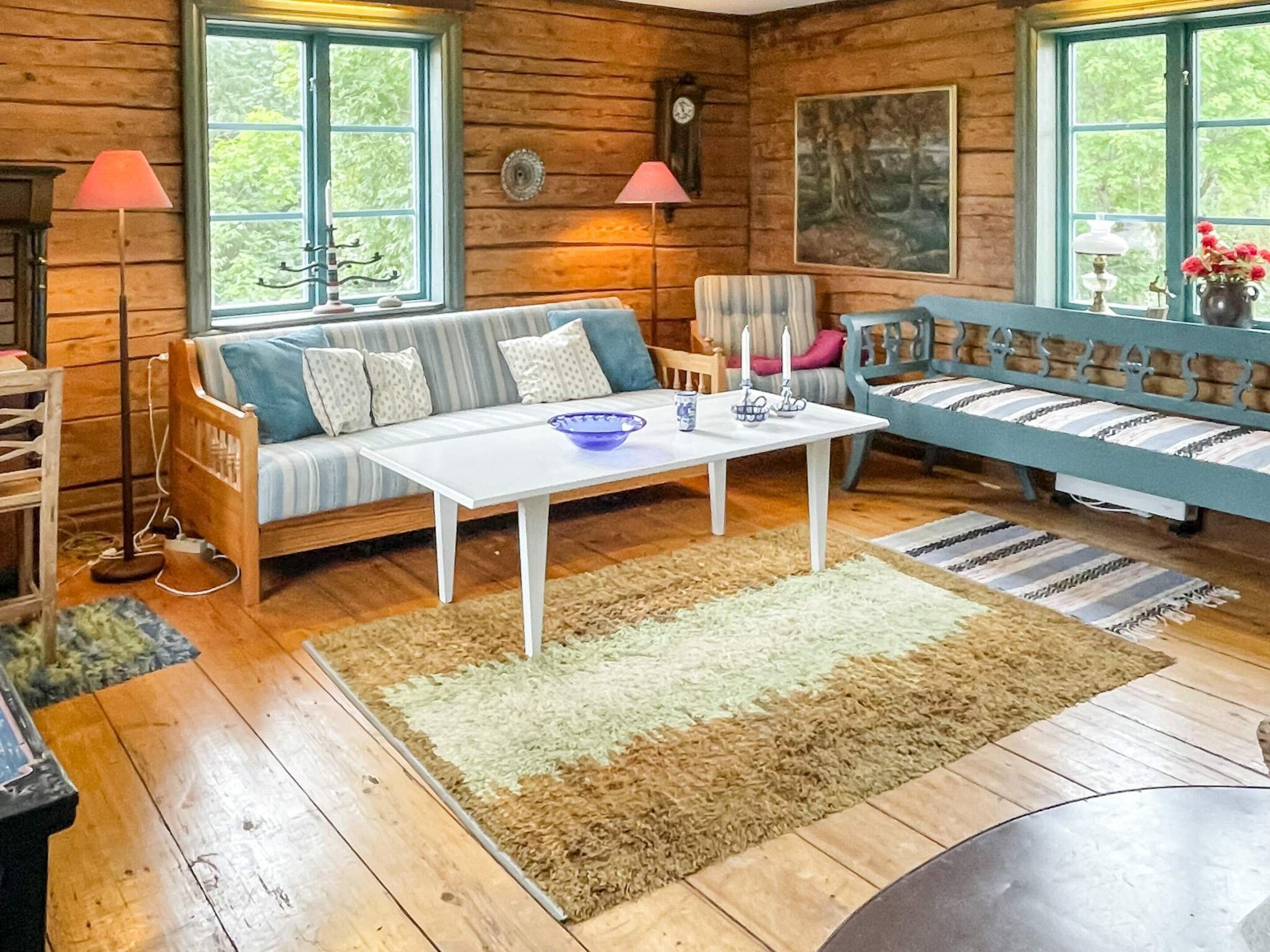 A cozy cabin interior with a wooden floor, a sofa, a table, and a chair.