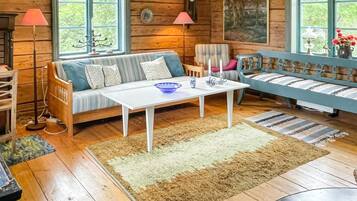 A cozy cabin interior with a wooden floor, a sofa, a table, and a chair.