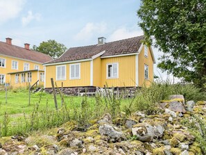 A yellow house with a red-tiled roof, surrounded by greenery and rocks. - 4 Person Holiday Home in Virserum (Virserum)