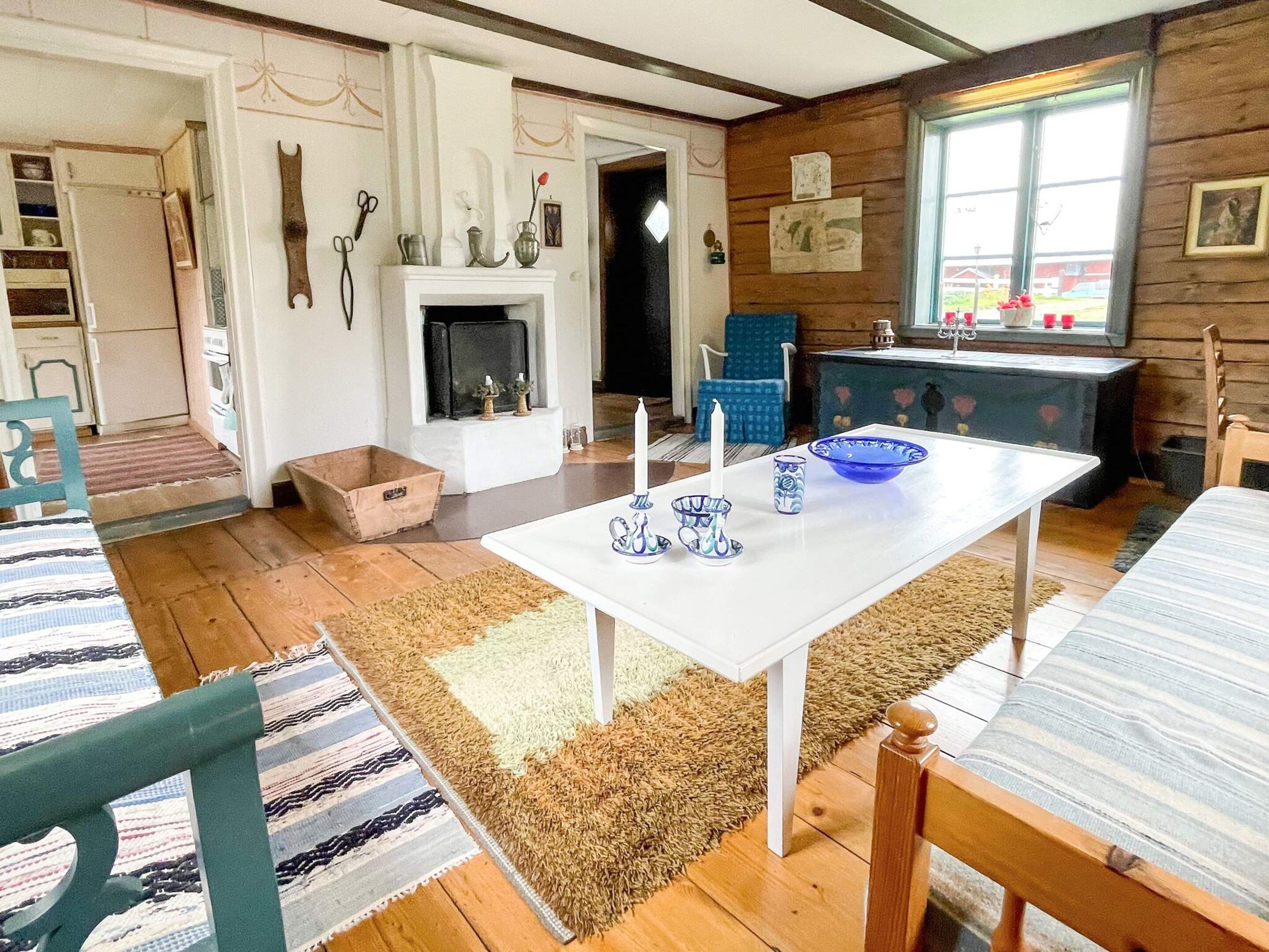 A cozy room with a fireplace, a dining table with blue and white patterned tableware, and a window with a view of the outside.