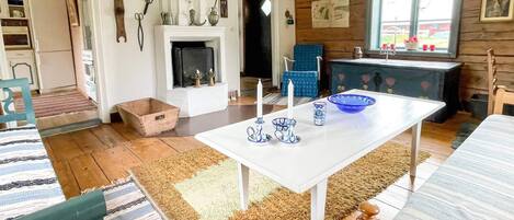 A cozy room with a fireplace, a dining table with blue and white patterned tableware, and a window with a view of the outside.