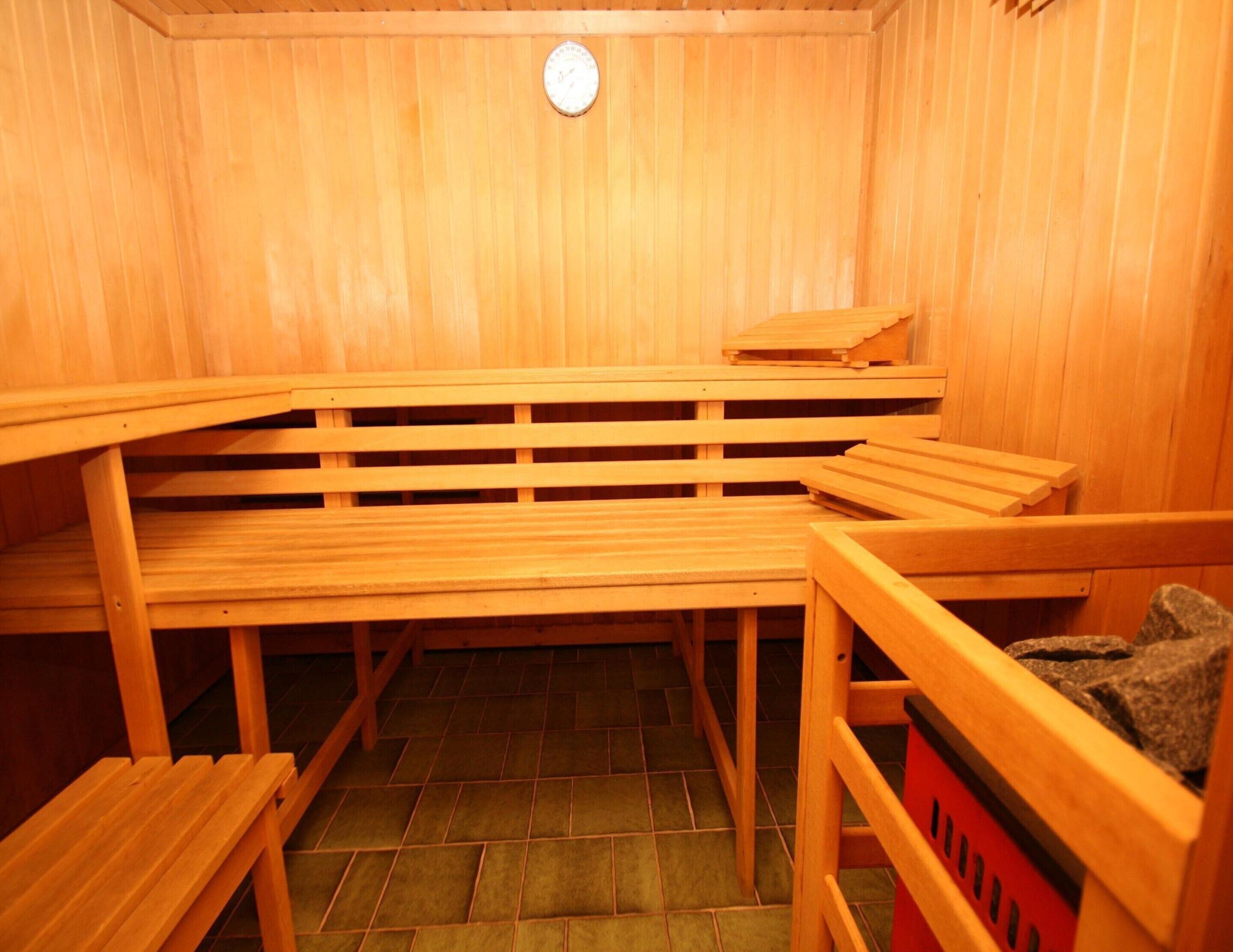 A sauna room with wooden benches and a red bench with a towel.