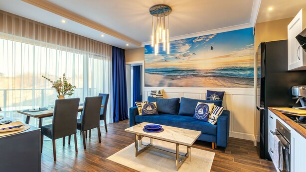 A modern living room with a blue sofa, dining area, and kitchen.