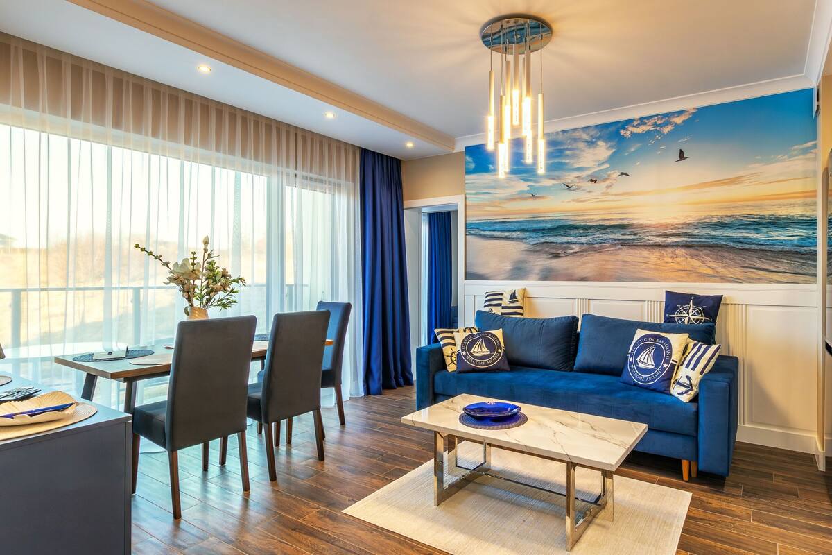 A modern living room with a blue sofa, dining area, and kitchen.