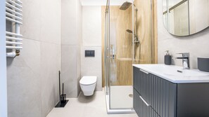 A modern bathroom with a glass-enclosed shower, a toilet, and a vanity with a mirror. - Sun & Snow Słoneczne Apartamenty (Ustronie Morskie)