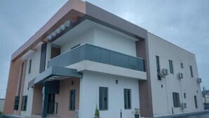 A modern two-story building with a balcony, large windows, and air conditioning units. - Peninsula Suites  (Bwari)