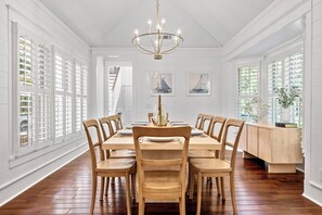 Ein Esszimmer mit Holztisch, Stühlen, einer Chandelierleuchtre und Bildern an den Wänden.