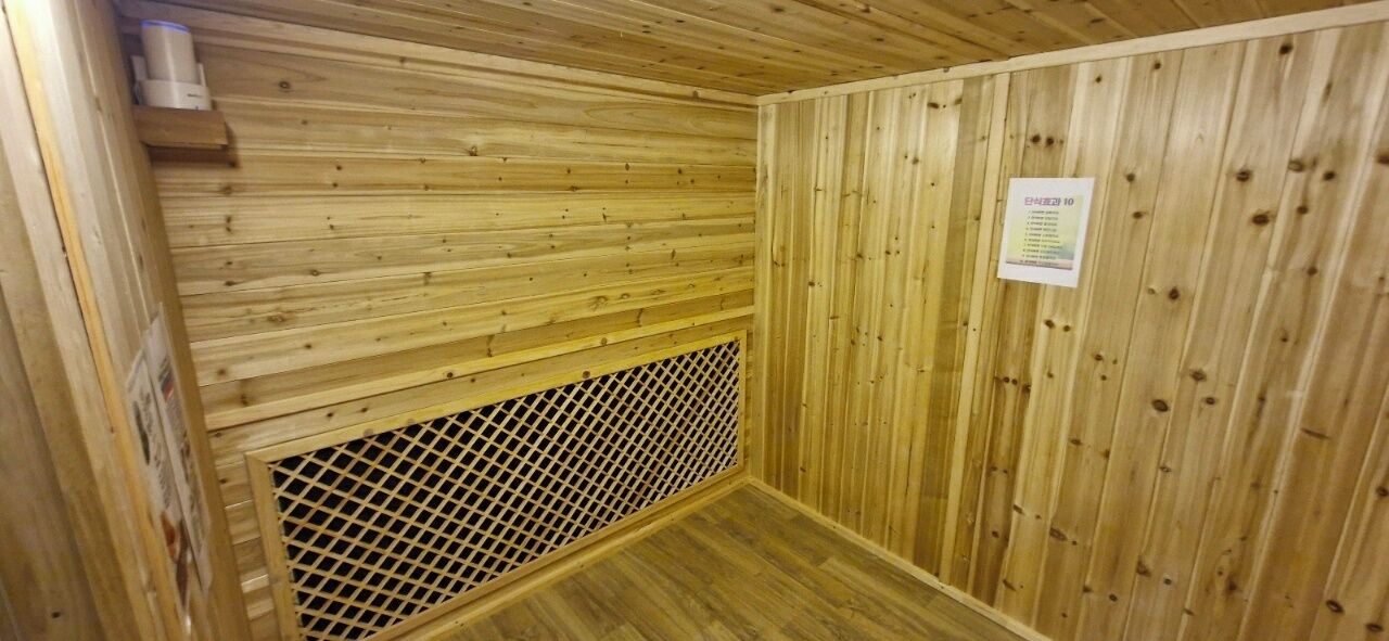 A sauna room with wooden walls and a ventilation grid.