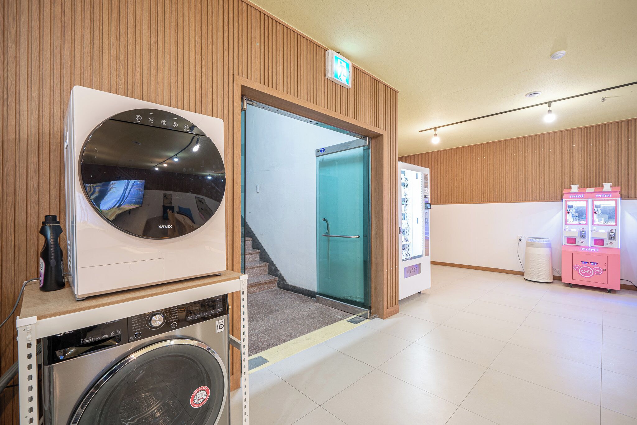 A laundry area with a washing machine, dryer, and a vending machine.