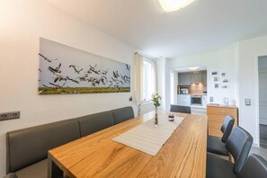 Enjoy meals with family and friends at the spacious dining table, surrounded by a beautiful abstract art piece and a touch of natural elegance.
