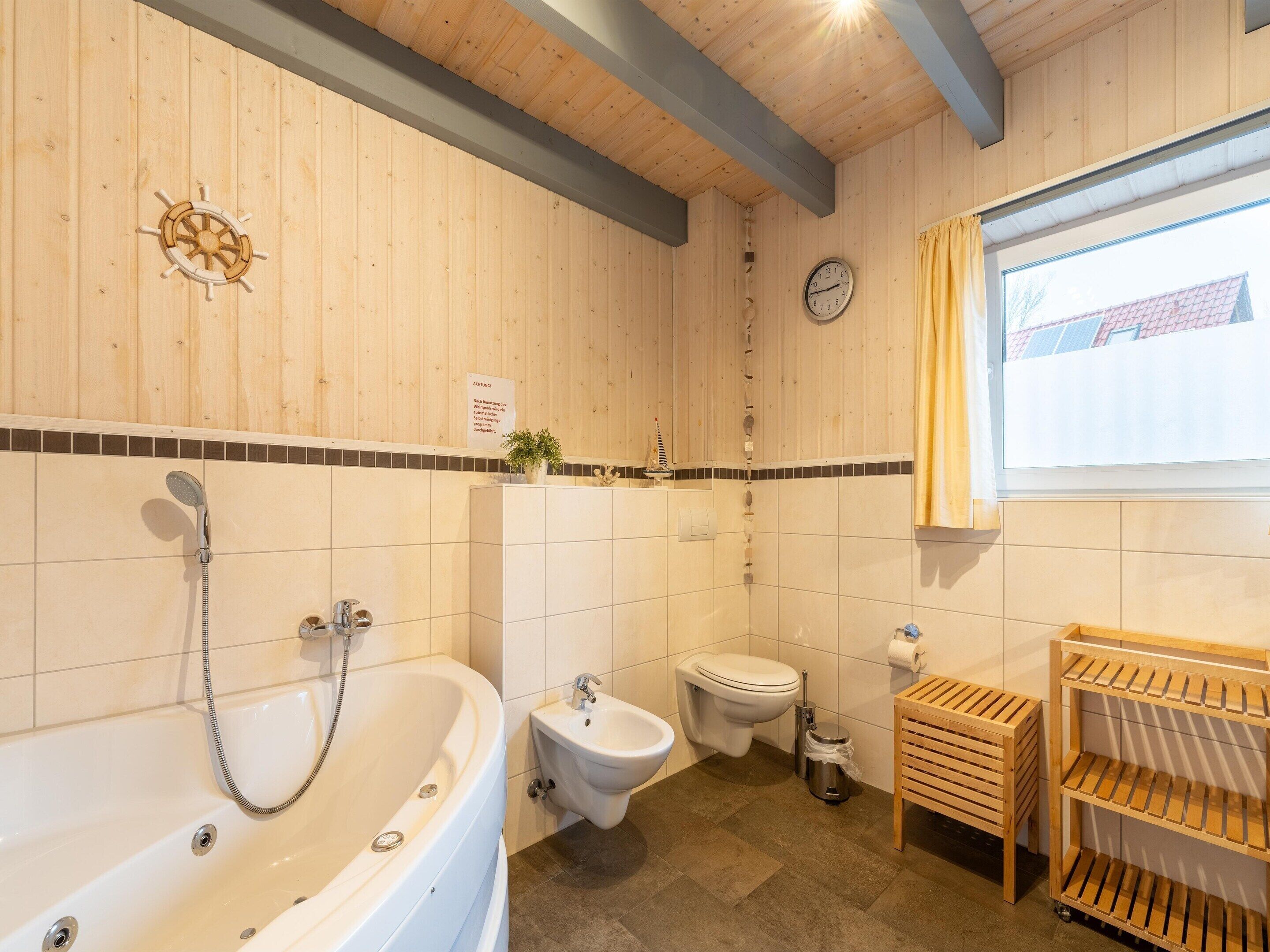 Un baño con bañera, bidé, inodoro y estantes de madera.
