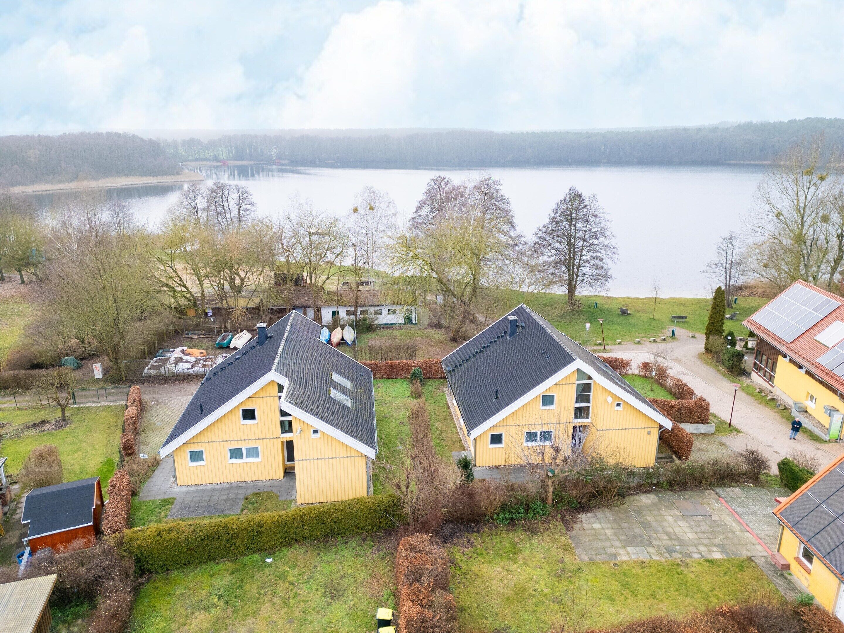 A lakeside property with two yellow buildings, a paved driveway, and a boat dock.