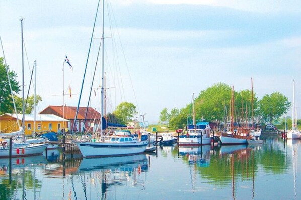 Boats docked in a serene marina surrounded by lush greenery and buildings.