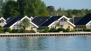 A row of modern, single-story houses with flat roofs, situated along a waterfront. - Ferienhaus im Ferienpark Mueritz (Rechlin)