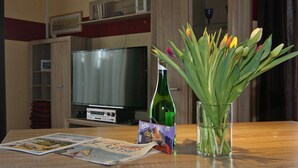 A living room with a television, a glass vase with flowers, and a magazine on the table. - Doppelhaushalfte in Bansin (Heringsdorf)