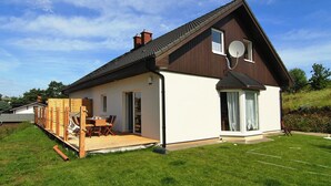 A modern two-story house with a sloped roof, a satellite dish, and a covered deck with outdoor furniture. - Doppelhaushalfte in Bansin (Heringsdorf)