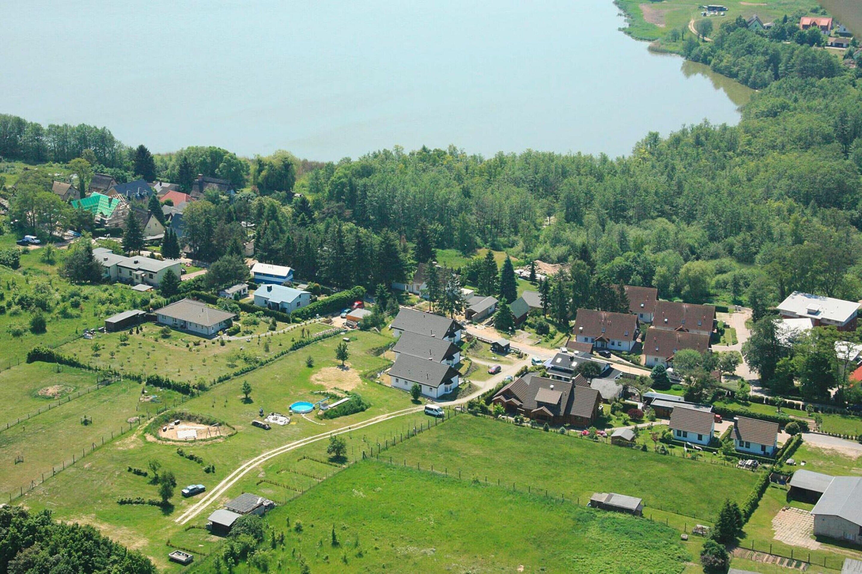 Vista aérea de una zona residencial con casas, un lago y vegetación circundante.