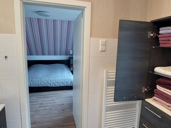 A bedroom with a bunk bed, a bedside table, a lamp, and a wardrobe with towels. - Ferienwohnung mit Seeblick am Gross Labenzer See (Warin)