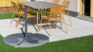 A patio with a table and chairs, a brick building, and a wooden fence in the background. - Well-kept and Cozy Polder House (Koksijde)