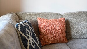 A grey sofa with patterned cushions and a framed photograph on the wall. - Well-kept and Cozy Polder House (Koksijde)