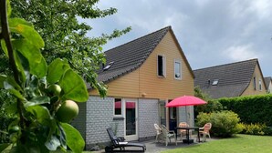 A house with a brick exterior, a tiled roof, and a small patio area with a table and chairs. - Nice Holiday Home Near Beach (Wemeldinge)