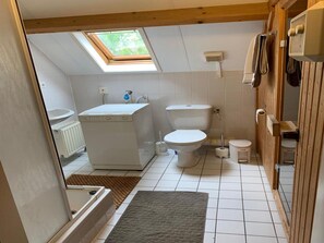 A compact bathroom with a skylight, a toilet, a sink, and a washing machine. - Nice Holiday Home Near Beach (Wemeldinge)