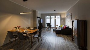 A modern living room with a dining area, a sofa, and a TV. - Exclusives Appartement auf Fehmarn (Fehmarn)