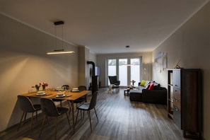 A modern living room with a dining area, a sofa, and a TV. - Exclusives Appartement auf Fehmarn (Fehmarn)