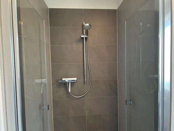 A shower with a handheld showerhead and a wall-mounted faucet. - Exclusives Appartement auf Fehmarn (Fehmarn)