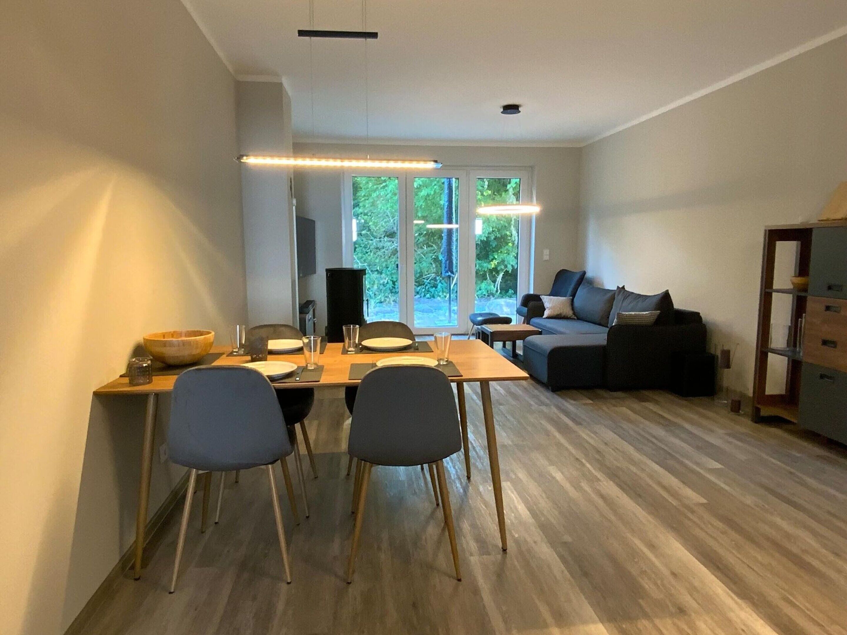 Un salon moderne comprenant un coin repas, de grandes fenêtres et une bibliothèque intégrée.