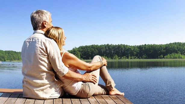 A couple sitting on a wooden dock overlooking a calm lake with a forested shoreline. - Apartment in Granzow Near the Lake (Mirow)
