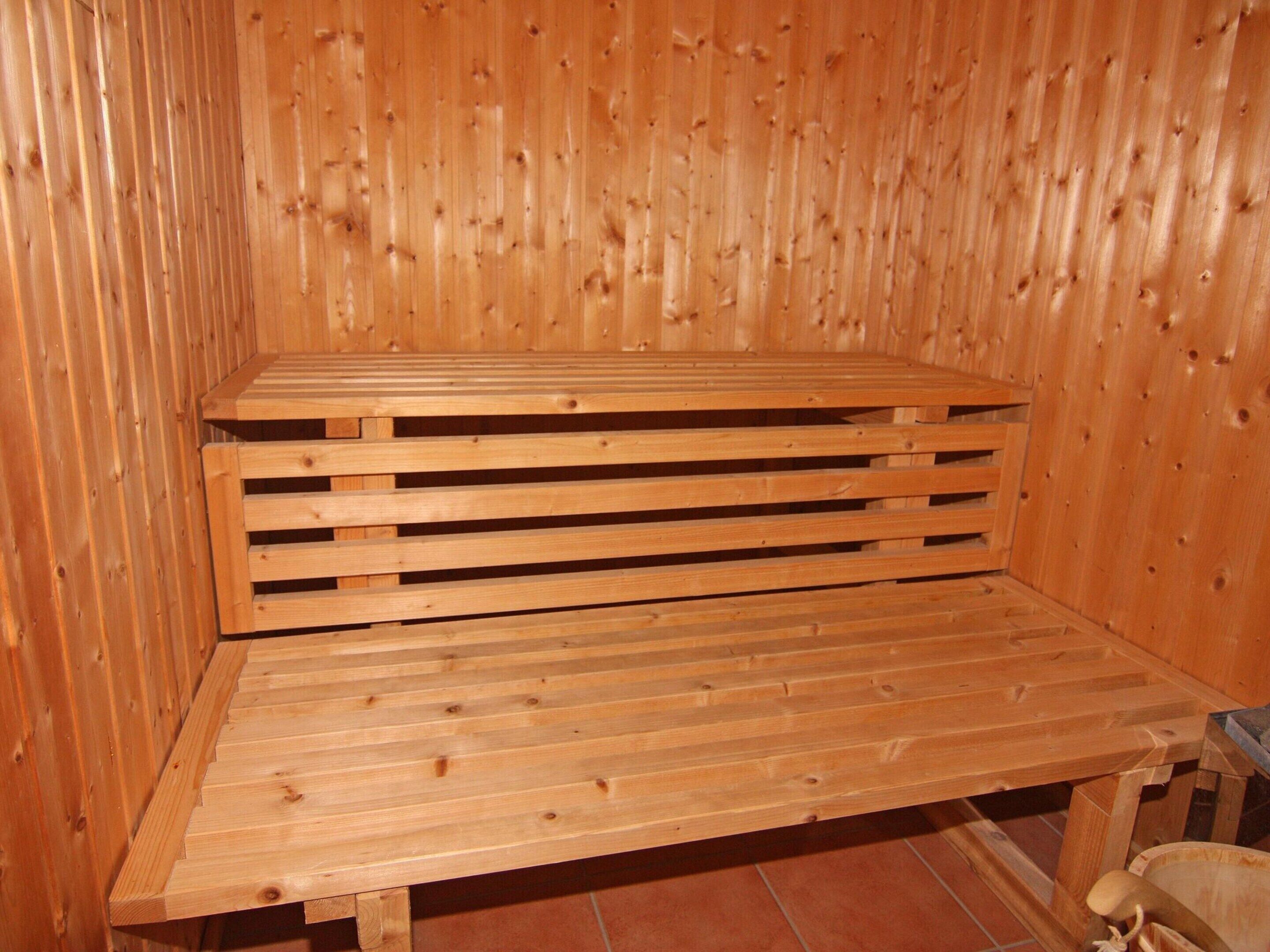 A wooden sauna with a bench and a small table.