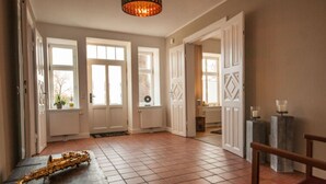 A spacious room with a tiled floor, large windows, and a door leading to another area. - Ferienhaus Kleine Freiheit auf Fehmarn (Fehmarn)