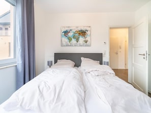 Een hotelkamer met een bed, een kaartwerk op de muur en uitzicht buiten.