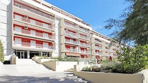 Ein mehrgeschossiges Wohngebäude mit Balkonen, einer Treppe und einer begrünten Anlage mit Pflanzen.