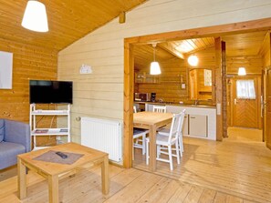 Un intérieur de chalet chaleureux comprenant un salon, un coin repas et une cuisine.