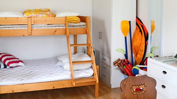 A bunk bed with a ladder, a wardrobe, and a dresser with paddles and a jacket. - 4 Person Holiday Home in Falkenberg (Falkenberg)
