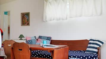 Una habitación acogedora con un banco de madera, una mesita y una ventana con cortinas blancas.