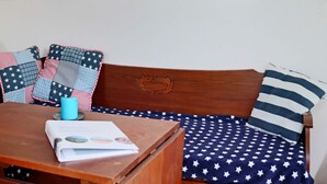 A wooden bench with a cushion featuring a star pattern, a blue mug, and a book on the bench. - 4 Person Holiday Home in Falkenberg (Falkenberg)