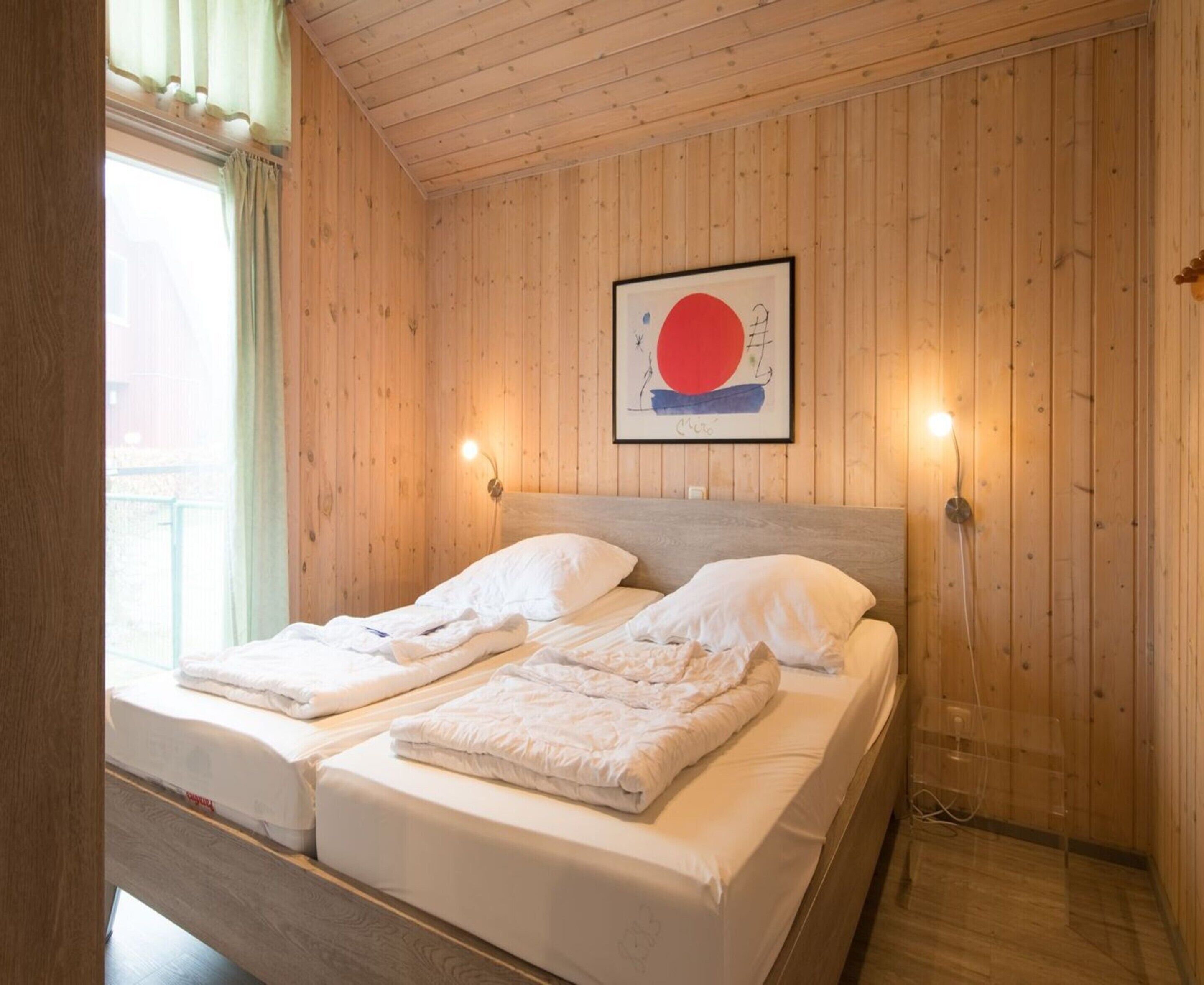 A double bed with two pillows and a framed artwork above it.